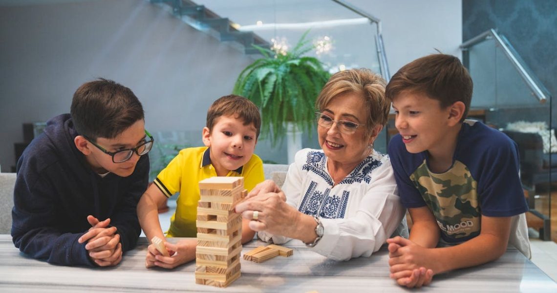 A joyful family moment with grandma and grandsons playing Jenga indoors, capturing quality time together.